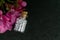 Close up image of homeopathic medicine bottle consisting white sugar balls and pink flower on dark background - Natural Homeopathy