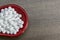 Close up image of homeopathic pills in red spoon on the wood surface