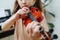 Close up image of a little girl learning to play violin, hitting strings with her finger