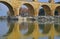 Close up image of lower arch level of Pont du Gard with clear reflection on Gardon River