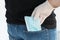 Close up image of man`s hand in white medical glove takes out blue medical mask from back pocket of his jeans,