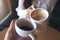 Close up image of a man and a woman clinking white coffee mugs