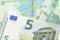 A close up image of a one Romanian leu bank note with a blue and green five euro, European bank note in macro