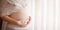 Close-up image of pregnant woman touching her belly with hands. Copy space