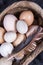 Close-up image of several native eggs with different shell colors next to each other  in a basket with bird feathers.