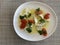 Close up image of a tomato and mozzarella salad topped with fresh basil leaves and drizzled with olive oil