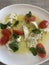 Close up image of a tomato and mozzarella salad topped with fresh basil leaves and drizzled with olive oil