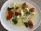Close up image of a tomato and mozzarella salad topped with fresh basil leaves and drizzled with olive oil