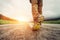 Close up image traveler feet on asphalt road in sunset time