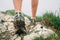 Close up image traveler feet in trekking boots on mountain rocky path at summer time