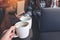 Close up image of two people clink white coffee mugs while working on laptop