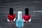 Close-up image of Two Red nail polish bottles and one colorless nail polish bottle