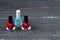 Close-up image of Two Red nail polish bottles and one colorless nail polish bottle on grey wooden background