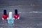 Close-up image of Two Red nail polish bottles and one colorless nail polish bottle on grey wooden background