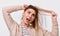 Close up image of upset young woman trying comb unruly hair pulling strands with raised hands screaming from pain and discomfort,