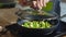 Close-up image of woman cooking fresh green asparagus in frying pan in olive oil and garlic