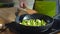 Close-up image of woman cooking fresh green asparagus in olive oil and garlic