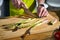 Close-up image of woman cooking in the kitchen, cutting fresh green asparagus on wooden cutting board