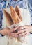 Close-up image of woman holding package of fresh baguettes.