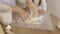 Close up image woman and little daughter knead dough with hands wooden table powdered with flour