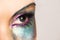 Close up of image of woman\'s turquoise eye with colorful rainbow makeup