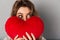 Close-up image of woman in t-shirt hiding behind joy heart