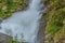 Close-up of an impetuous jump of a waterfall in the midst of mountain vegetation