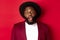 Close-up of impressed Black man with beard staring at camera, drop jaw and looking amazed, standing over red background