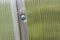 Close-up of incorrect fastening of a polycarbonate sheet with a screw. Damage to polycarbonate due to improper fastening