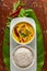 Close-up of Indian cooked rice with kadi or kadhi over the banana fresh green leaf. Garnished with curry-patta leaves, red chili