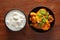 Close-up of Indian vegetarian dish of spicy Potato and Tomato curry garnished with green coriander fresh leaves with curd. over wo