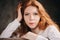 Close up indoor portrait of adorable thoughtful young redhead woman with freckles and long hair