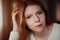 Close up indoor portrait of adorable thoughtful young redhead woman with freckles and long hair