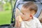 Close up Infant baby boy eating cracker biscuit sitting on stroller in nature park