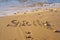 Close-up of inscription word Sicily written on wet sand of beach seashore coastline after tide near waves at sunset.