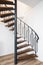 Close up of a iron exterior spiral staircase on the side of a modern house with white wall