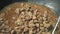 Close-up of the iron ladle stirring stew in the large cauldron