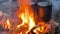 Close-up of iron pots of water over a large fire. Travel kitchen. Yellow-orange flames.