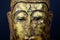 Close up of isolated ancient gold paint wood Buddha head face of thai statue in buddhist temple