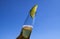 Close up of isolated bottleneck with sparkling yellow beer and a slice of lime against cloudless deep blue sky