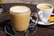 Close up of isolated brown dutch milk coffee koffie verkeerd in transparent glass mug and white espresso cup