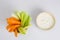 Close up isolated flat lay top view shot of party snack food. A bowl of crunchy orange carrot and juicy green celery sticks with a