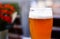 Close up of isolated glass german weed beer, white foam with bubbles, blurred background, red bokeh. Germany