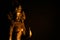 Close up of isolated illuminated hindu Shiva god golden bronze statue with raised hand on blank black background