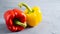 Close up isolated red and yellow ripe papers on cement gray background. Bright bell peppers. Pepper sprinkled with water