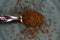 Close up of isolated spoon full with dry cumin seeds on scratched old blue china dish