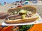 Close up of isolated typical dutch bread roll with raw fresh soused herring, gherkin, mustard and onions. Blurred beach background