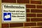 Close up of isolated white sign on red Brick wall. German text: VideoÃ¼berwachung. Diese Fassade wird wegen Vandalismus Ã¼berwacht