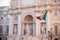 Close Up of Italian Flag on the Blurred Trevi`s Funtain Background