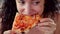 Close Up Italian-looking woman in a red dress eagerly eating and enjoying Italian pizza while in a restaurant. The